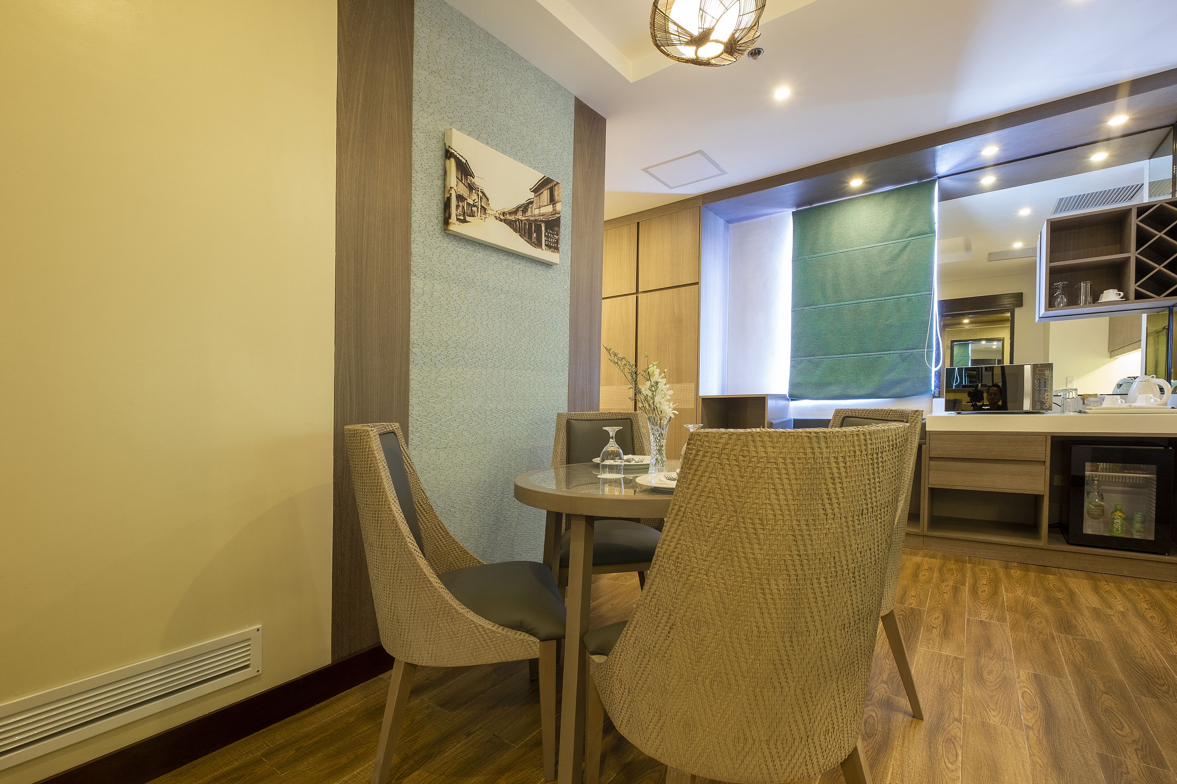 A dining area with a round table, two chairs, and a vase with flowers.