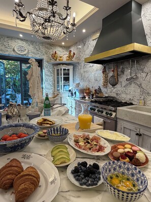 Una cocina bien equipada con encimeras de mármol, una araña y vistas al exterior.