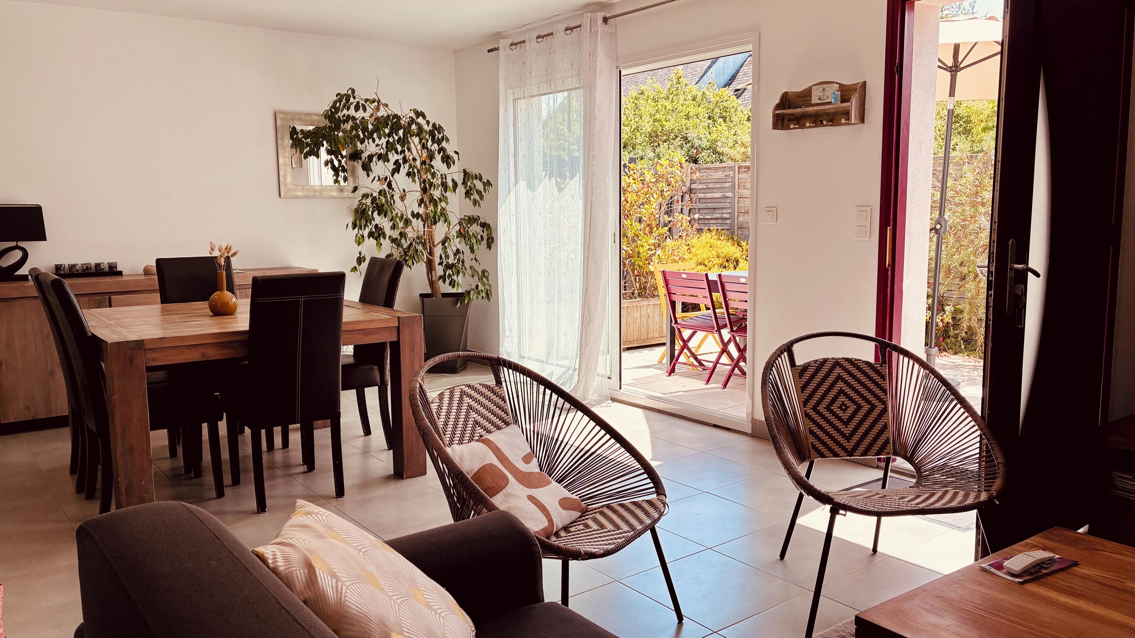 A dining area with a table and chairs, a sofa, and a potted plant.