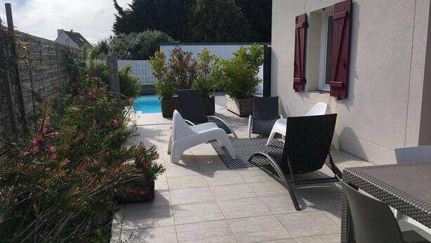 Un patio con piscina, mobiliario exterior y plantas en macetas.