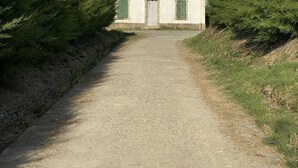 Un faro con un sendero de grava que lo lleva, rodeado de vegetación.
