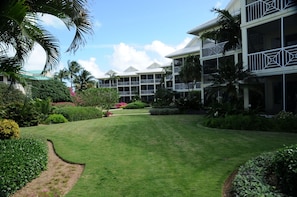 Un hotel de varios pisos, con balcones y elaboradas barandillas, y exuberante jardinería tropical.