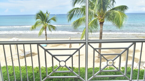Ein Balkon mit Blick auf den Strand, Palmen und das Meer.