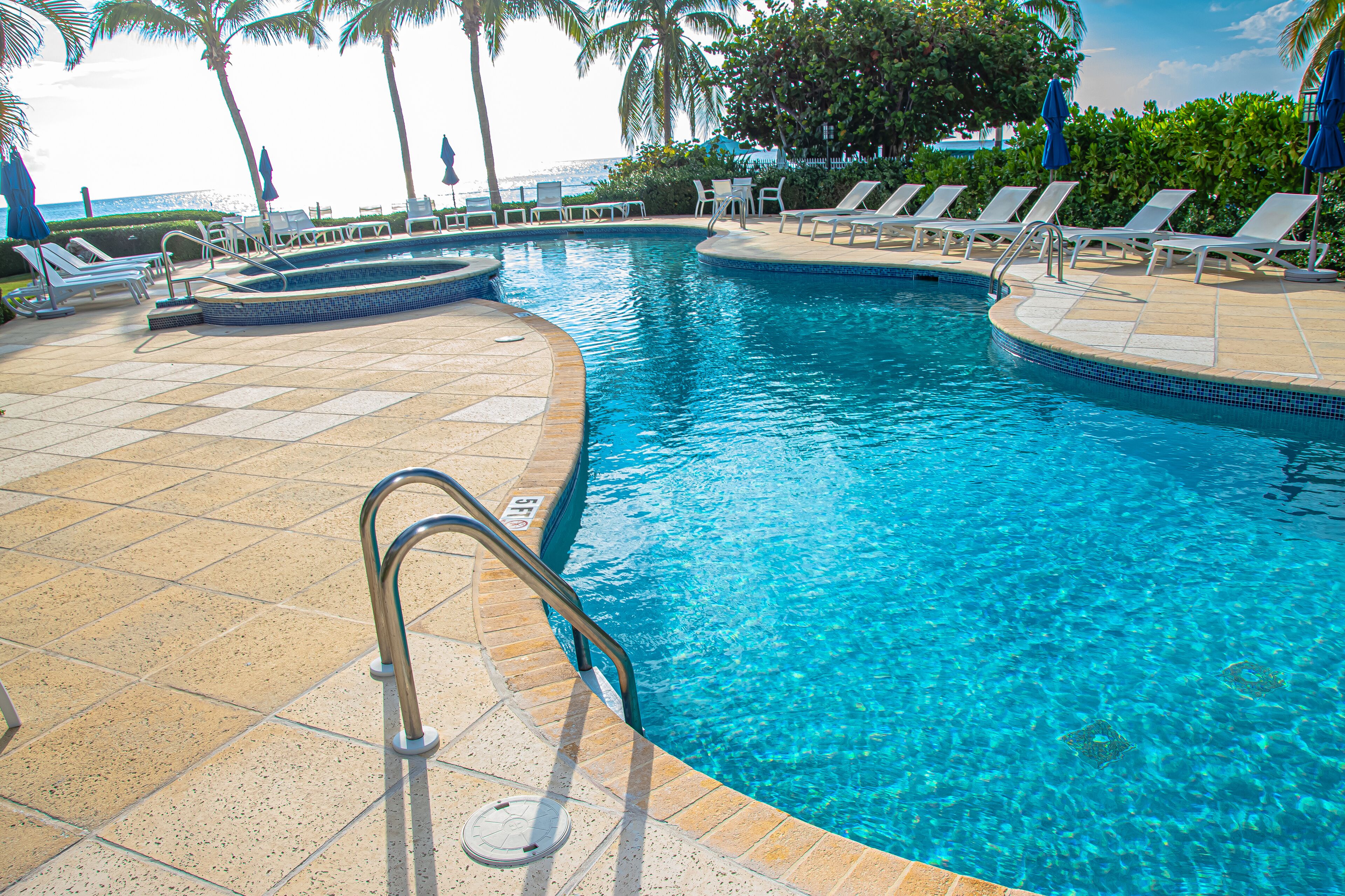 A swimming pool with a tiled deck, lounge chairs, and a lifeguard stand.