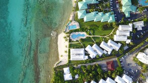 Ein Luftbild eines Resorts mit mehreren Gebäuden, einem Strand und einem Schwimmbad.