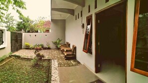 A courtyard with a paved area, a wooden bench, and potted plants. - Adikarta Guesthouse Janti (Banguntapan)