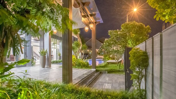 An outdoor area with a pool, potted plants, and a pathway leading to a building entrance. - Dai An Phu Villa (Da Nang)