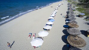 A beach with rows of umbrellas and beach chairs, a sandy shore, and the ocean. - Dai An Phu Villa (Da Nang)