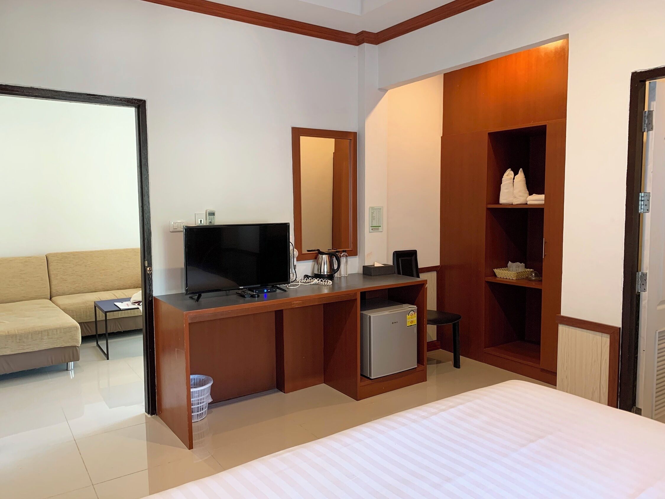 Een hotelkamer met een bed, een televisie, een bureau met een computer, een kleine koelkast, een bank en een kledingkast.
