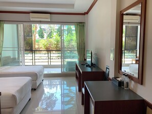 A hotel room with two beds, a desk, a computer, and a large window with a view of greenery. - Breezehill Khao Kho Hotel (Khao Kho)