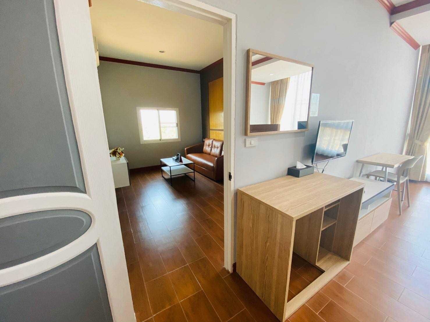 Un salon moderne avec un canapé en cuir marron, une table basse en bois, un téléviseur et un coin repas comprenant une petite table et des chaises.