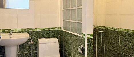 A bathroom with a toilet, sink, and shower area.