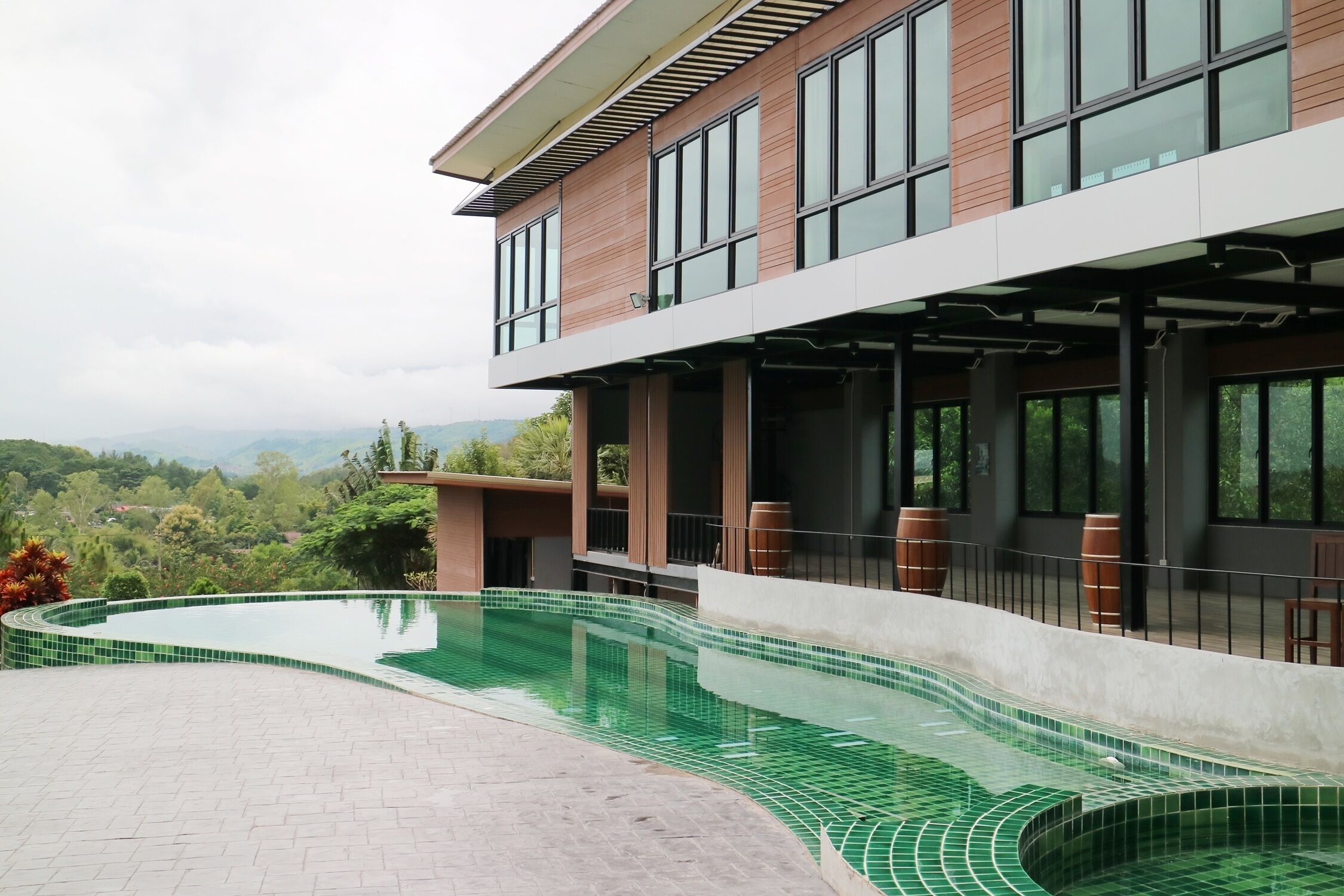 A modern building with a swimming pool, large windows, and a view of the landscape.