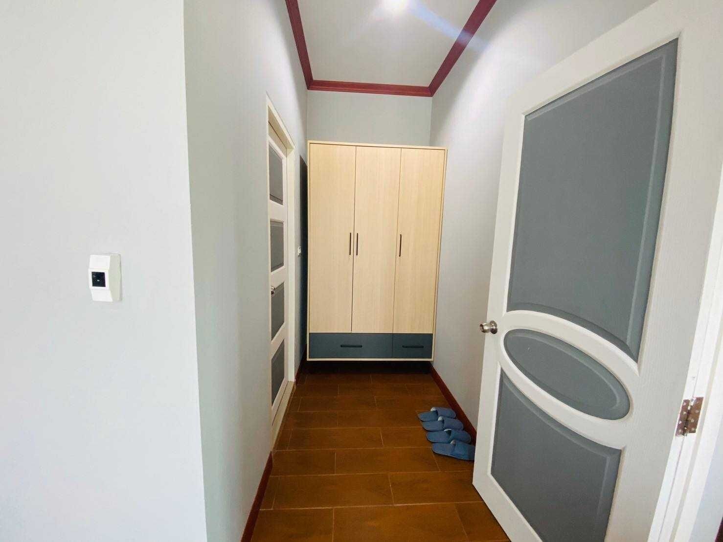 A hallway with a wardrobe, a door, and a light switch.