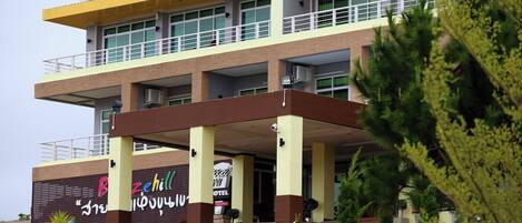 Un hotel de varios pisos con entrada cubierta, balcones y un cartel que indica que es un hotel.