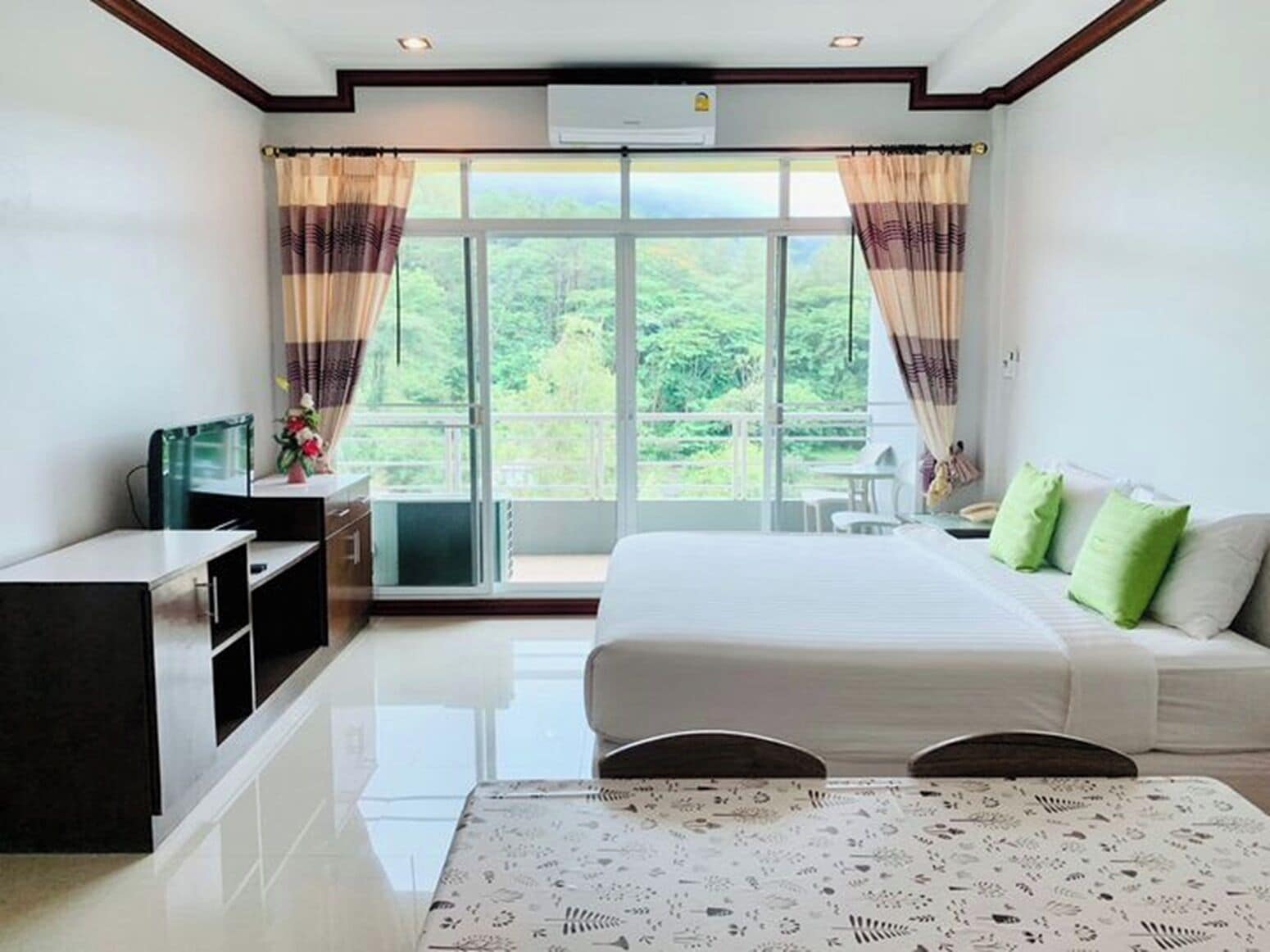 Une chambre d’hôtel avec un grand lit, un bureau, une chaise et un balcon avec des rideaux.