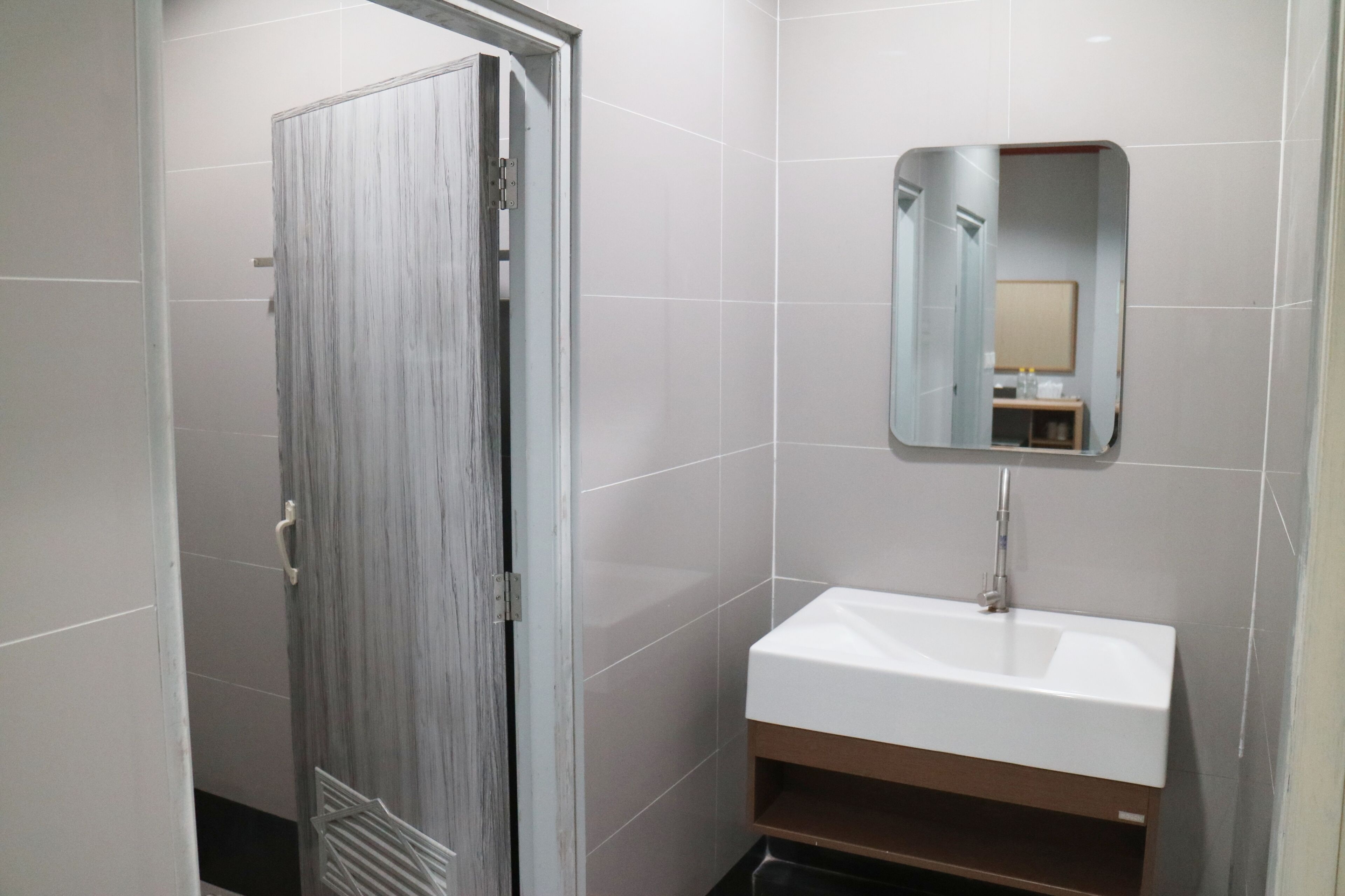 A bathroom with a white sink, a mirror, and a door.