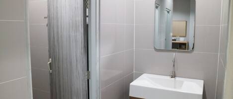 A bathroom with a white sink, a mirror, and a door.