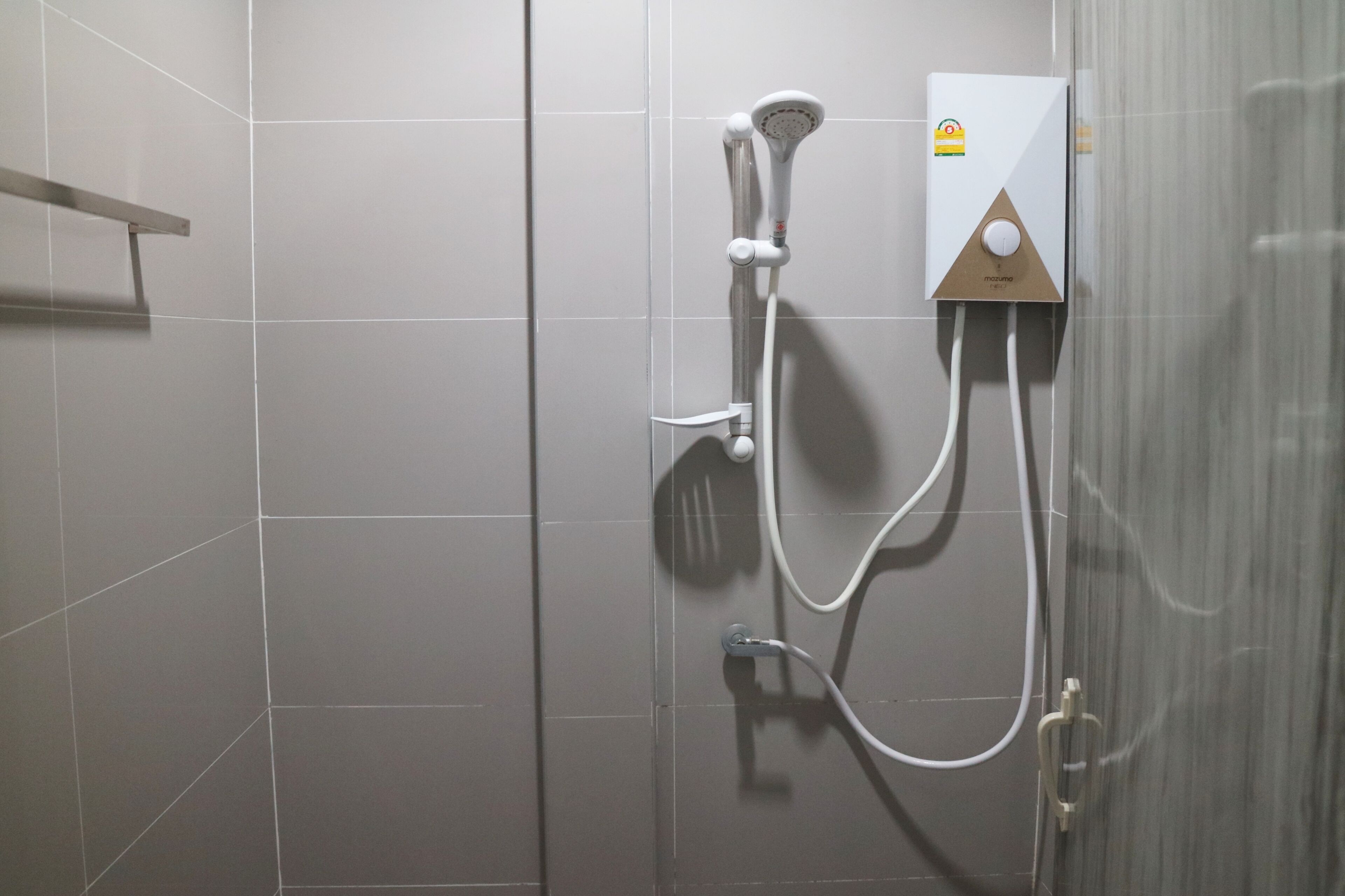 A shower with a handheld showerhead and a wall-mounted control panel.