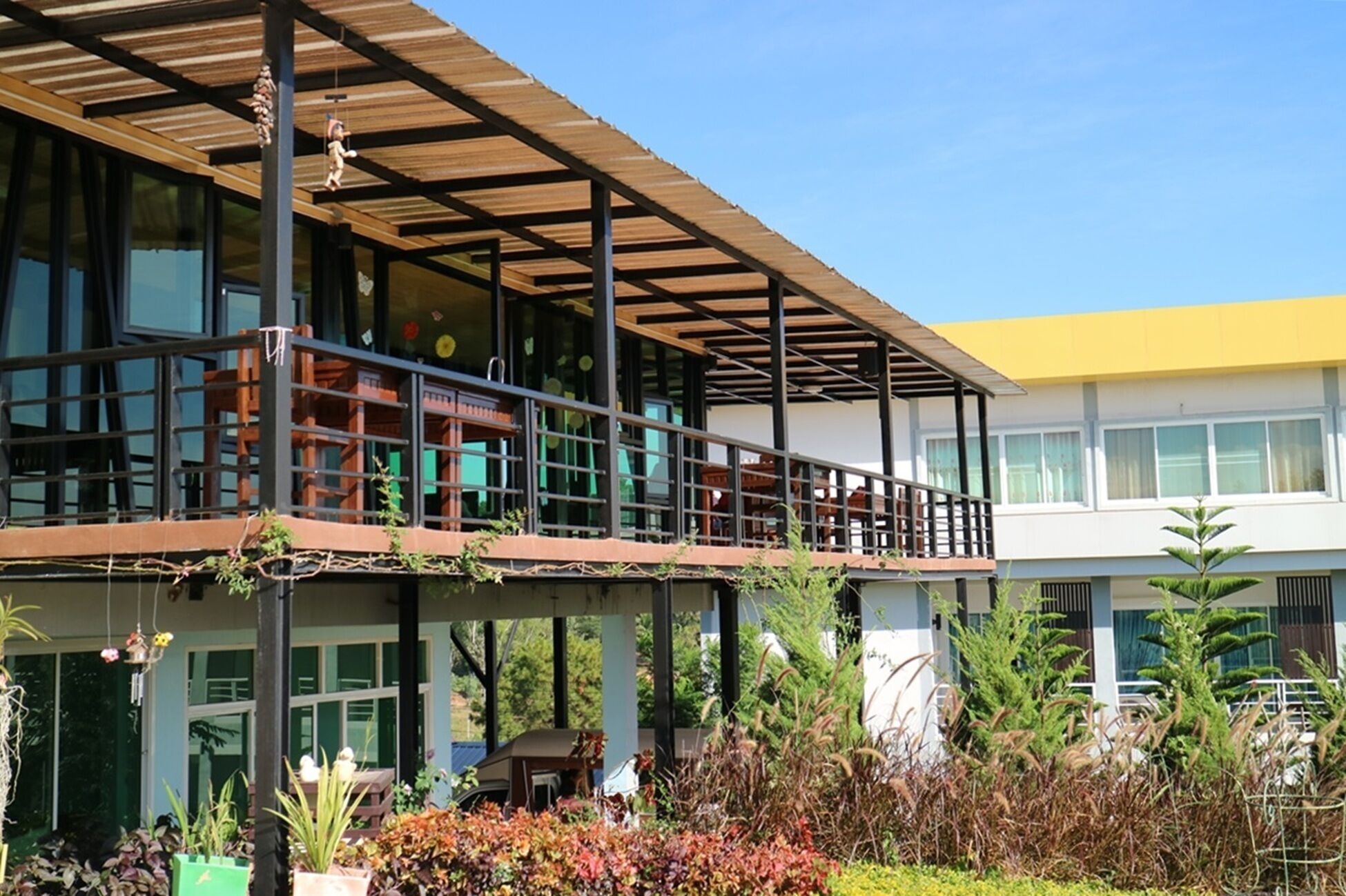 A modern building with a covered outdoor area, large windows, and a yellow roof.