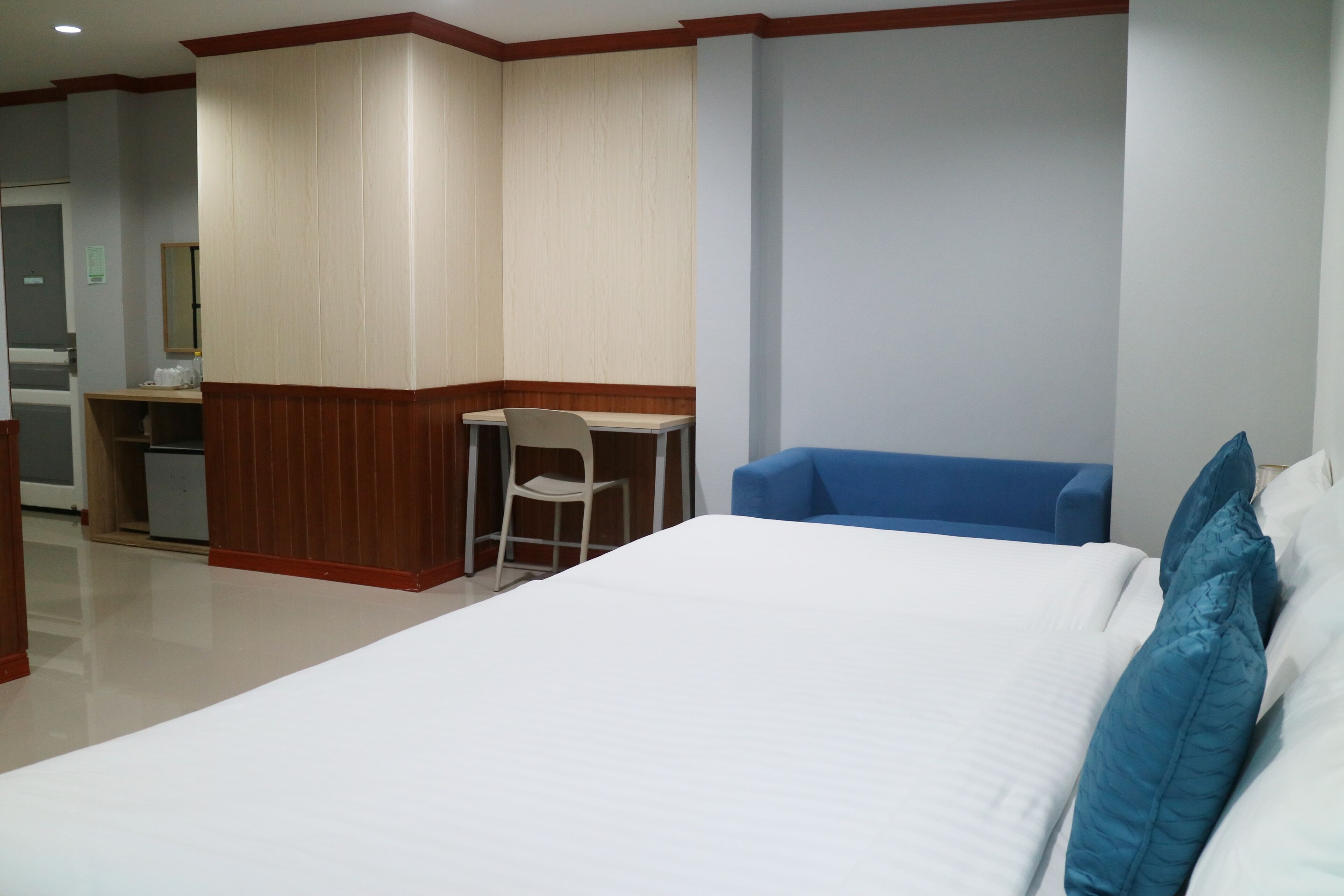 Una habitación de hotel con una cama, un escritorio, una silla y un sofá azul.