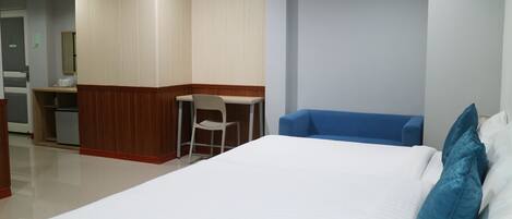 Una habitación de hotel con una cama, un escritorio, una silla y un sofá azul.