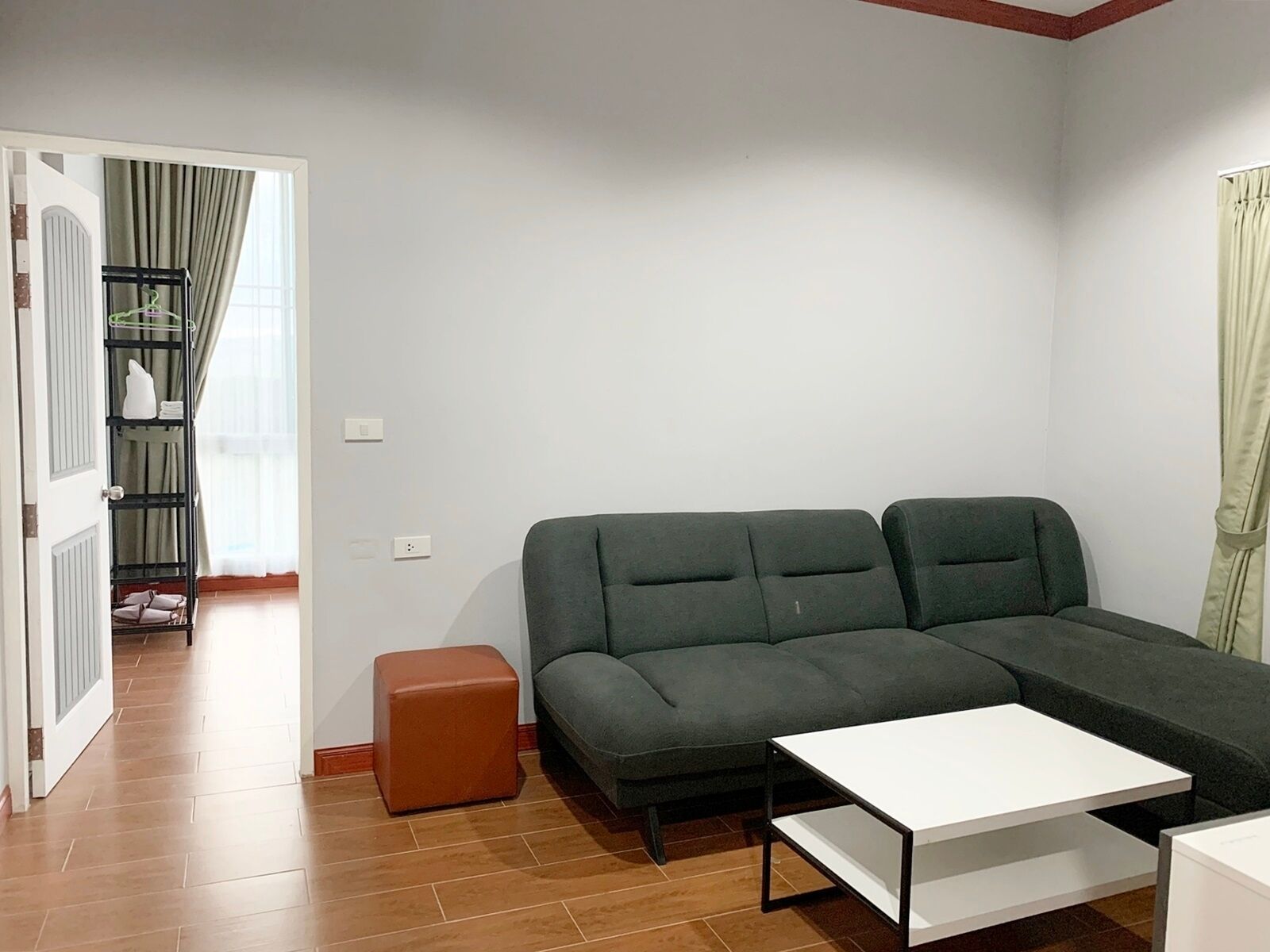A living room with a sectional sofa, a small ottoman, and a white coffee table.