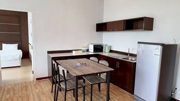 Cocina compacta con mesa, sillas, refrigerador y microondas.