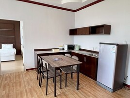 Cocina compacta con mesa, sillas, refrigerador y microondas.