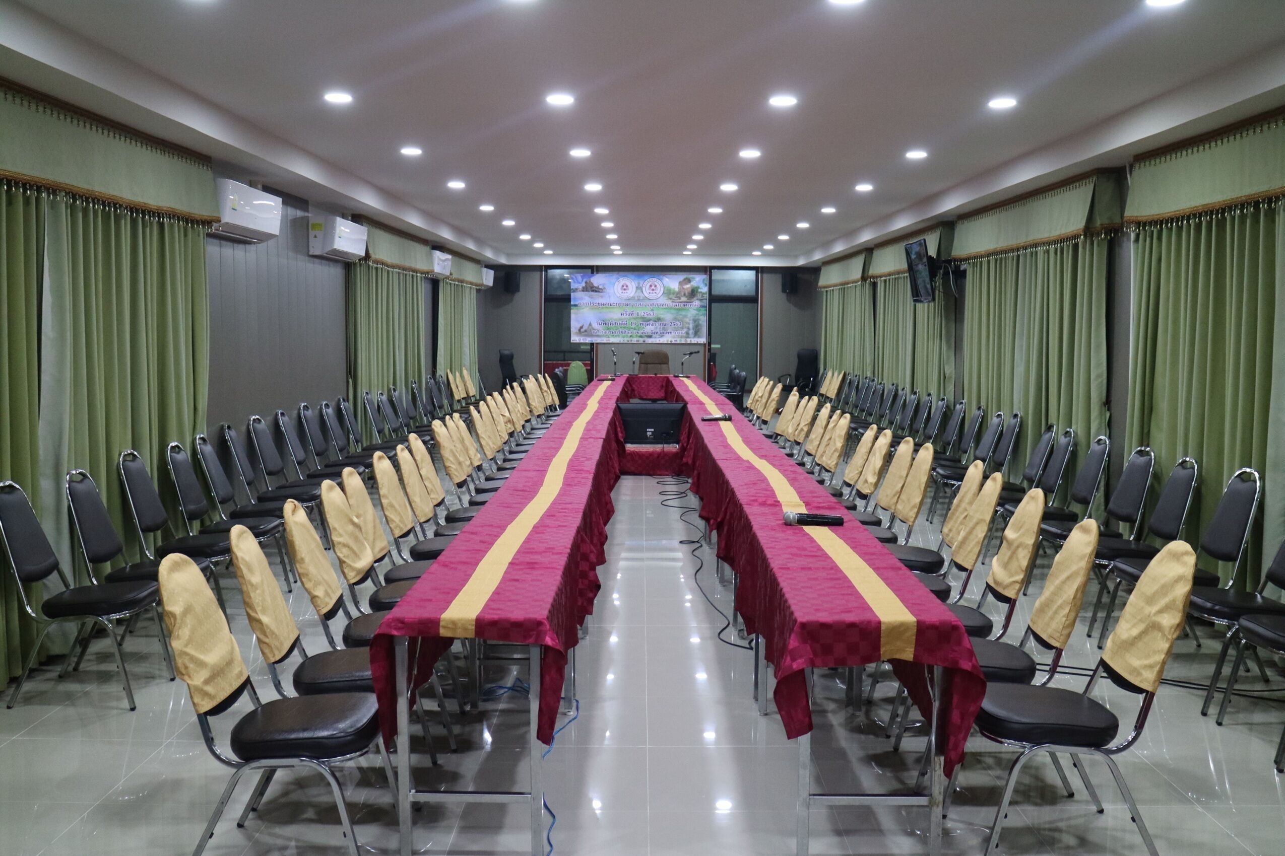 A conference room with a long table, chairs, and a screen at the front.
