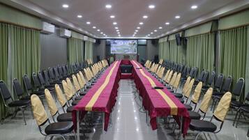 A conference room with a long table, chairs, and a screen at the front.