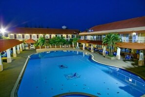 A hotel with a swimming pool, outdoor seating, and a covered area with umbrellas. - Homeland Resort (Phetchabun)