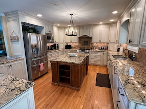 A spacious kitchen with granite countertops, stainless steel appliances, and wooden cabinets. - Fryars' Green Guest House at Tennessee RiverPlace (Chattanooga)