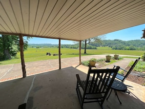 A covered patio with a view of a green field and trees. - Fryars' Green Guest House at Tennessee RiverPlace (Chattanooga)