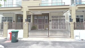 A two-story building with a gated entrance, a satellite dish, and a trash bin. - Noor Homestay (Kangar)