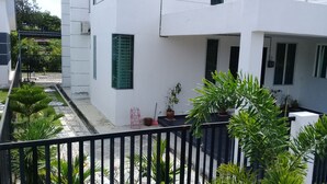 A modern white building with a balcony, potted plants, and a black metal fence. - Noor Homestay (Kangar)