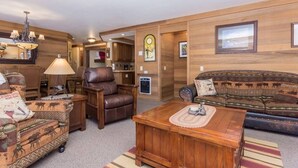 Ein gemütliches Wohnzimmer mit Ledersessel, gemustertem Sofa und Couchtisch aus Holz.