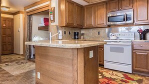 Eine Küche mit Holzausstattung, einer Granitarbeitsplatte, einer Mikrowelle, einem Backofen und einem Wasserkocher.