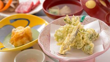 Una mesa con diversos platos, incluyendo tempura, sashimi y un tazón de arroz.