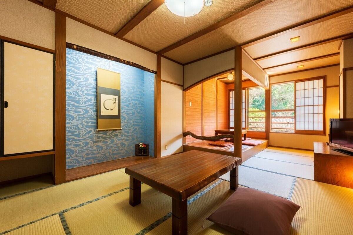 A traditional Japanese room with tatami flooring, sliding doors, and a television.
