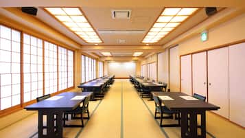 A conference room with long tables and chairs, large windows, and a tiled floor.