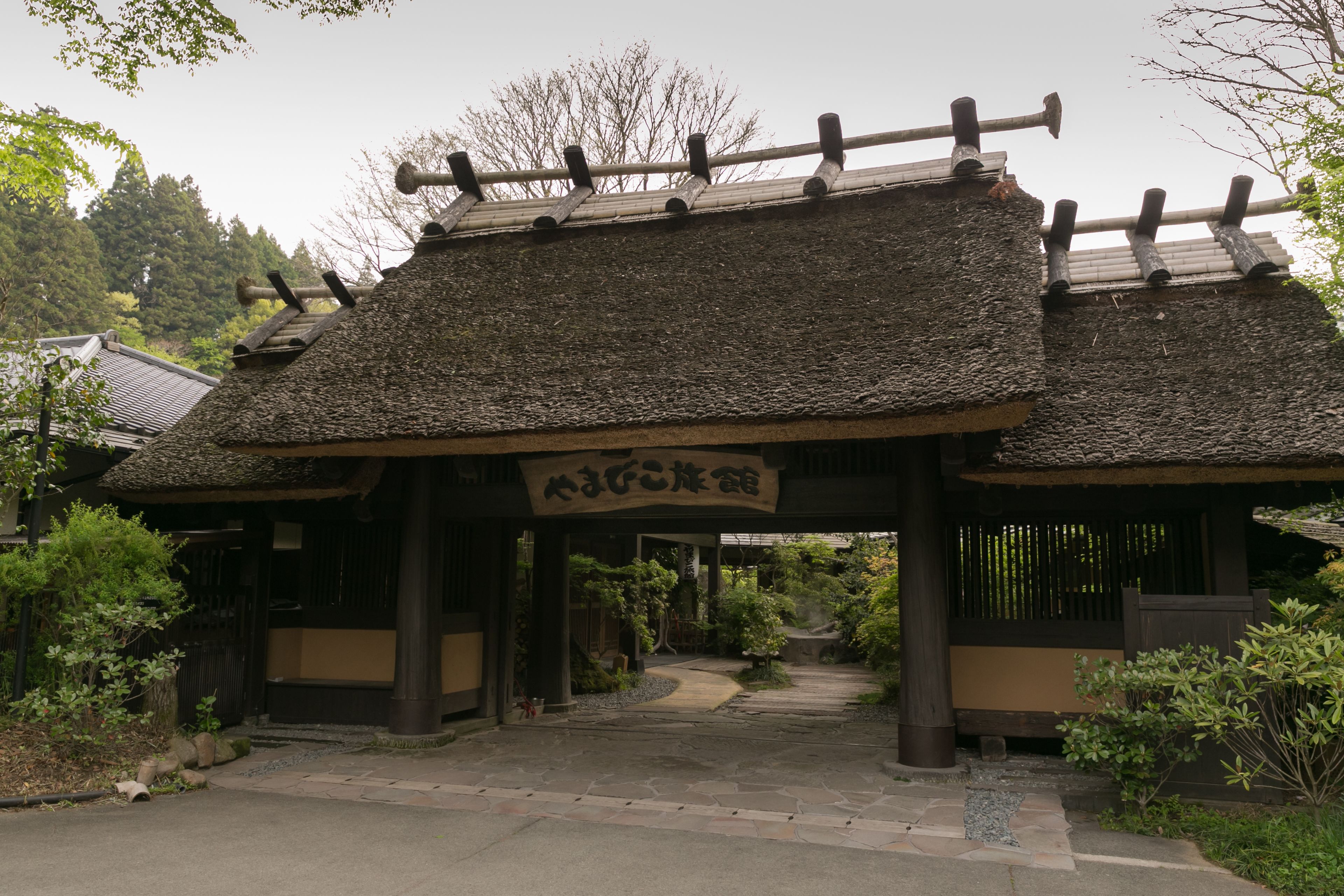 A traditional Japanese building with a tiled roof and a wooden entrance gate.