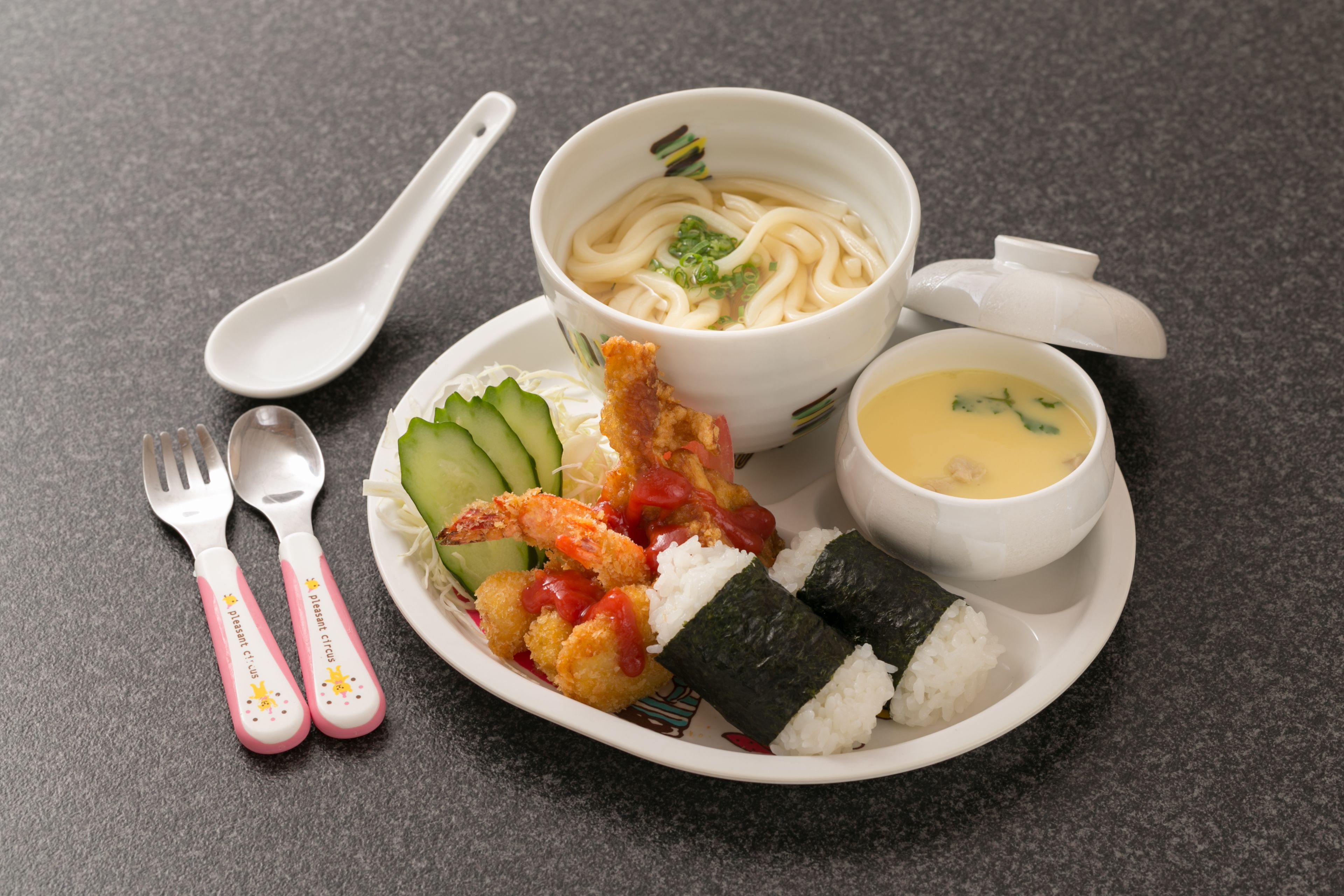 A meal with noodles, soup, rice, and vegetables on a plate.