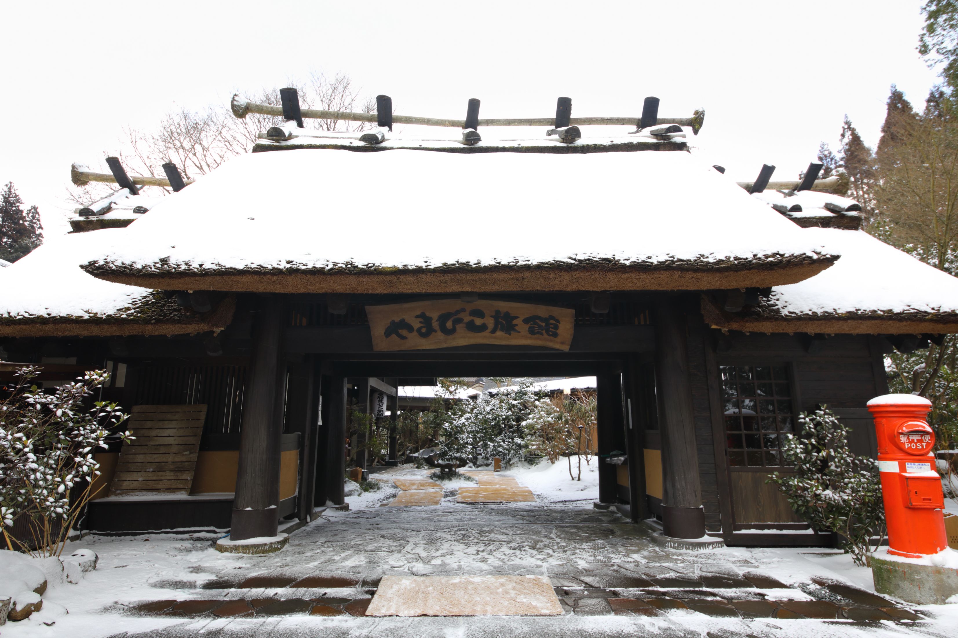 Un bâtiment traditionnel japonais, avec une entrée enneigée et une enseigne en bois.