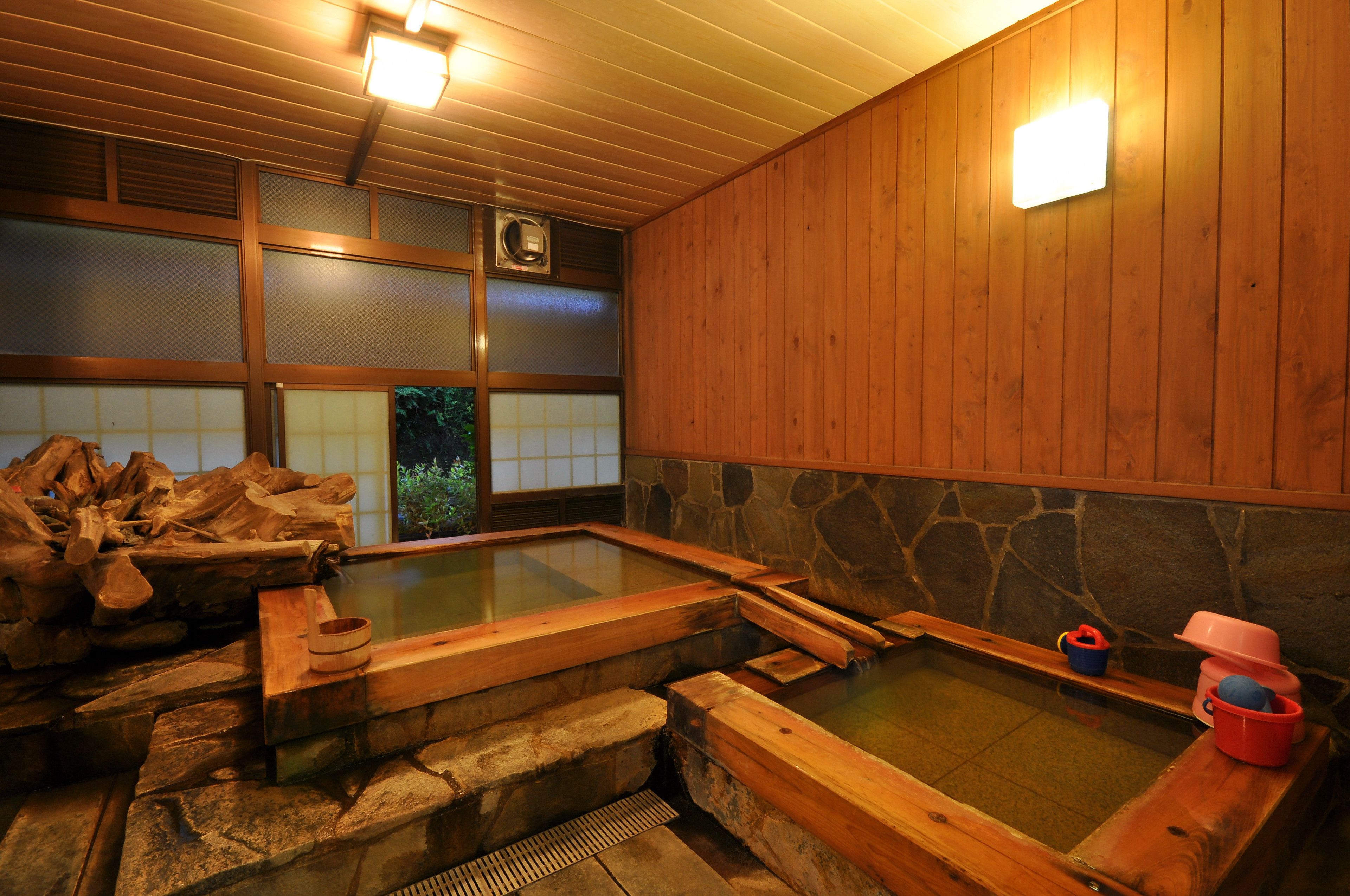 Un onsen japonés tradicional con bancos de madera y paredes de piedra.