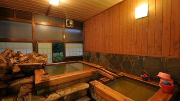 Un onsen japonés tradicional con bancos de madera y paredes de piedra.