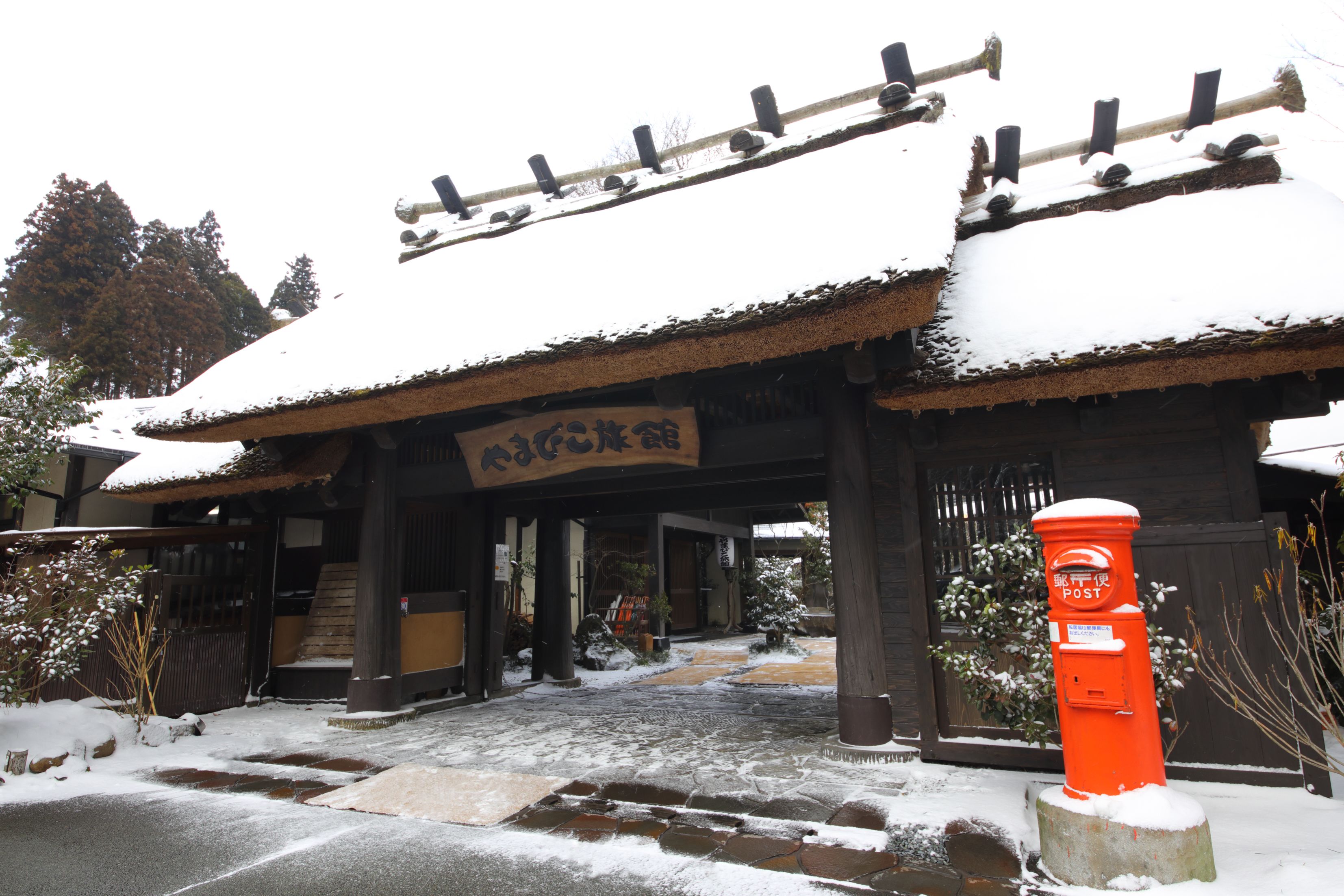 A traditional Japanese building with a snow-covered entrance and a red post box.