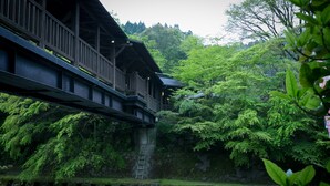 A traditional wooden bridge over a river, surrounded by lush greenery and a stone wall. - Kurokawa Onsen Yamabiko Ryokan (Minamioguni)