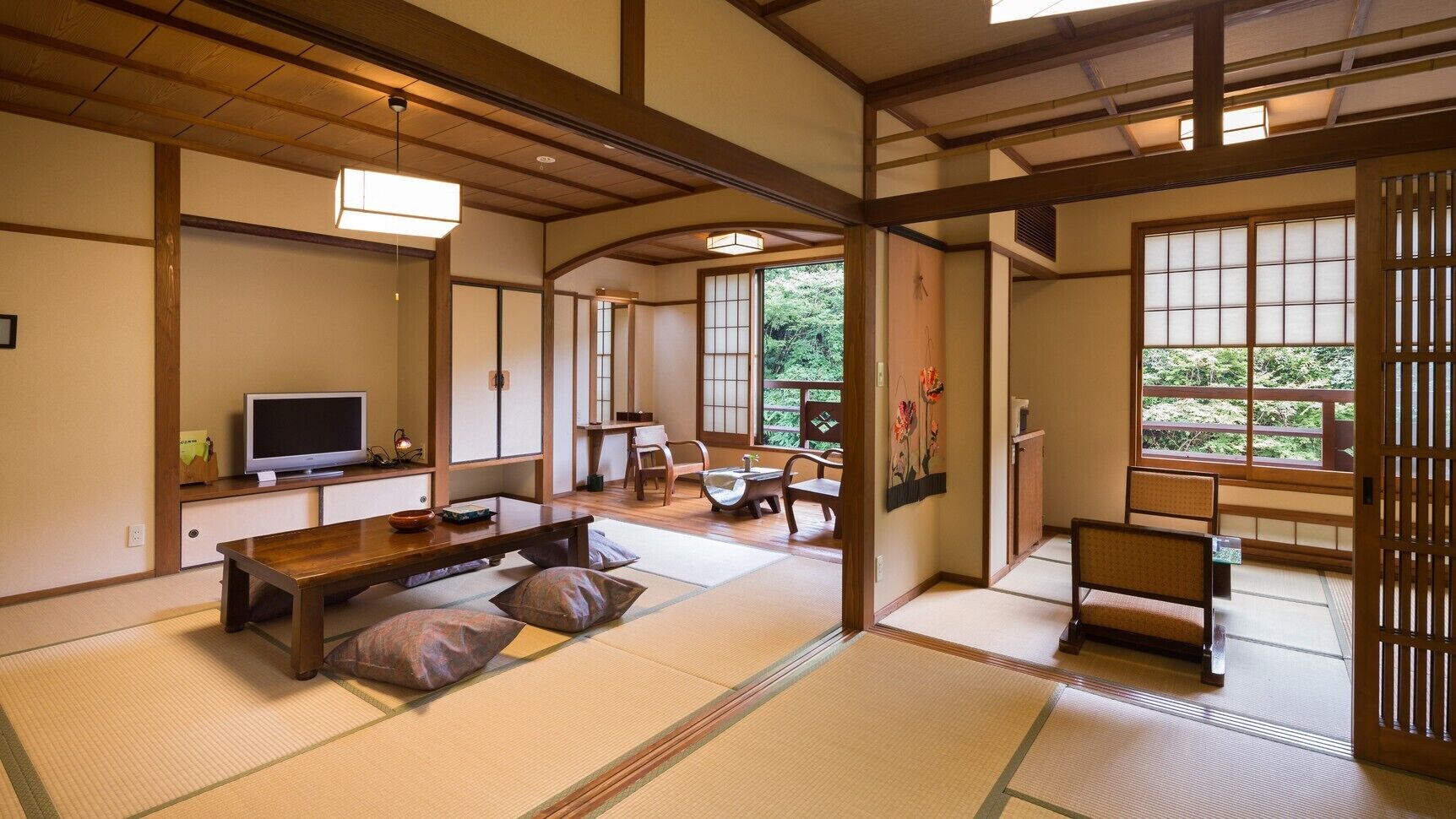 A traditional Japanese room with tatami flooring, a television, a low wooden table, and a sliding door.