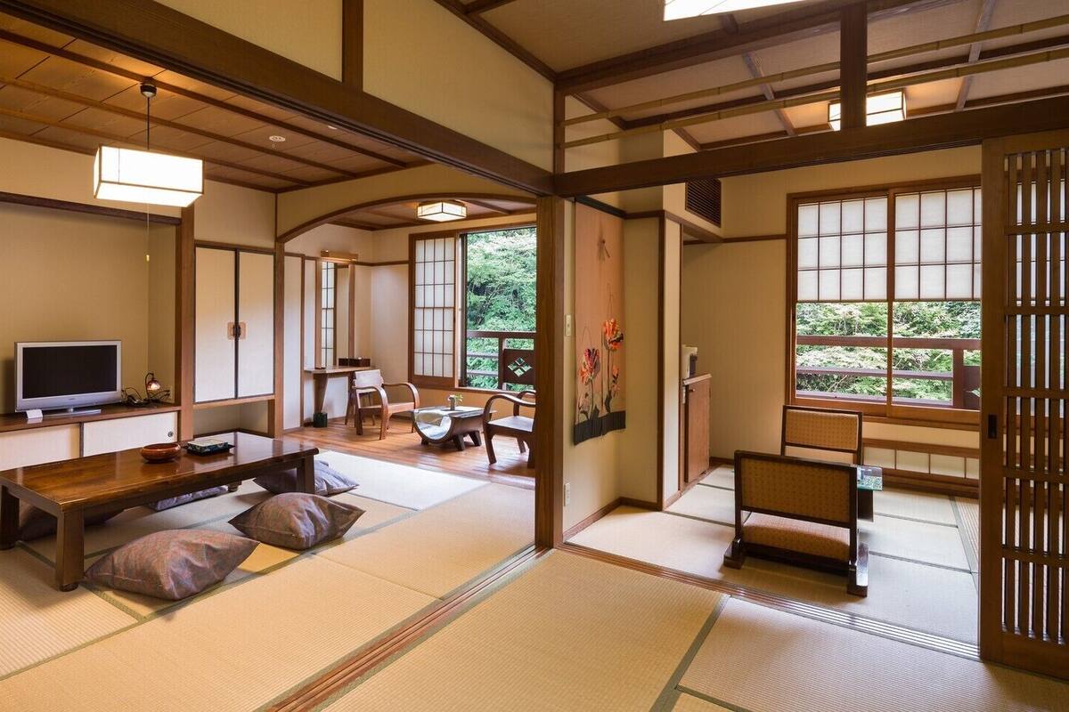 A traditional Japanese room with tatami flooring, a television, a low wooden table, and a sliding door.